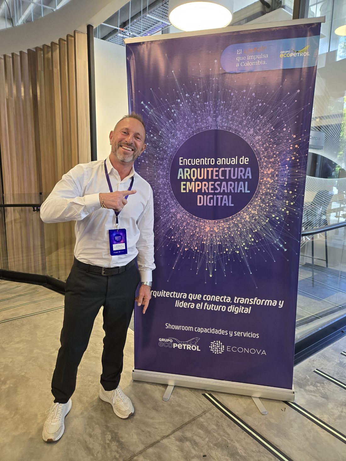 Patrick Knoedler pointing, laughing, at the roll-up banner of the Encuentro anual de Arquitectura Empresarial Digital