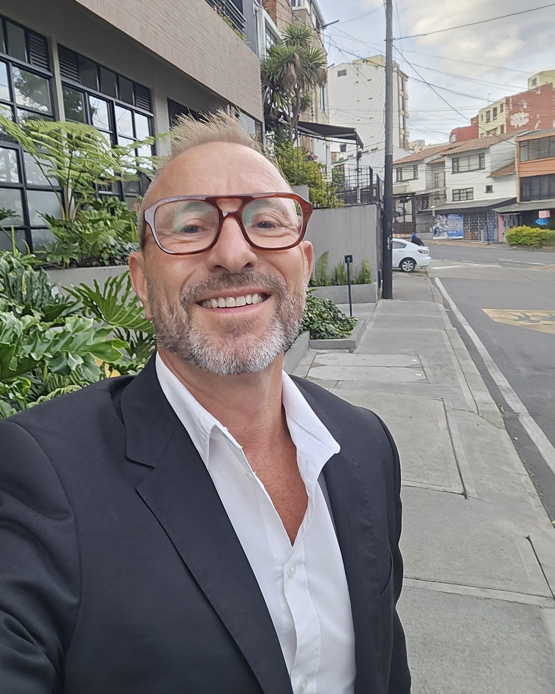 Patrick Knoedler smiling in a blazer and white shirt on a street in Bogotá